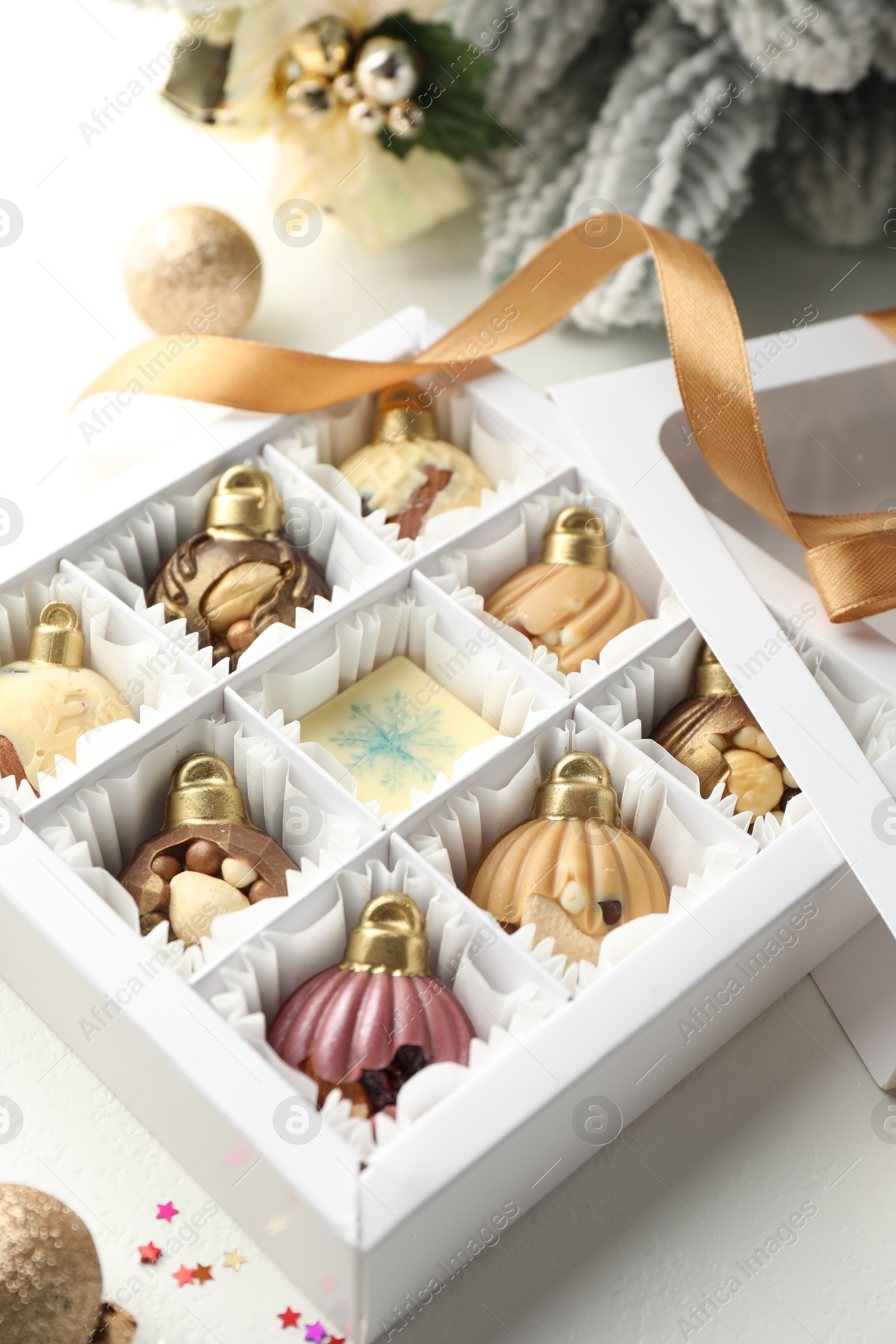 Photo of Box with tasty chocolate candies in shape of baubles and Christmas decor on white background, closeup