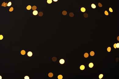 Photo of Blurred view of golden lights on black background, bokeh effect