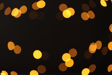 Photo of Blurred view of golden lights on black background, bokeh effect