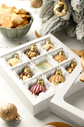 Photo of Box with tasty chocolate candies in shape of baubles and Christmas decor on white background, closeup