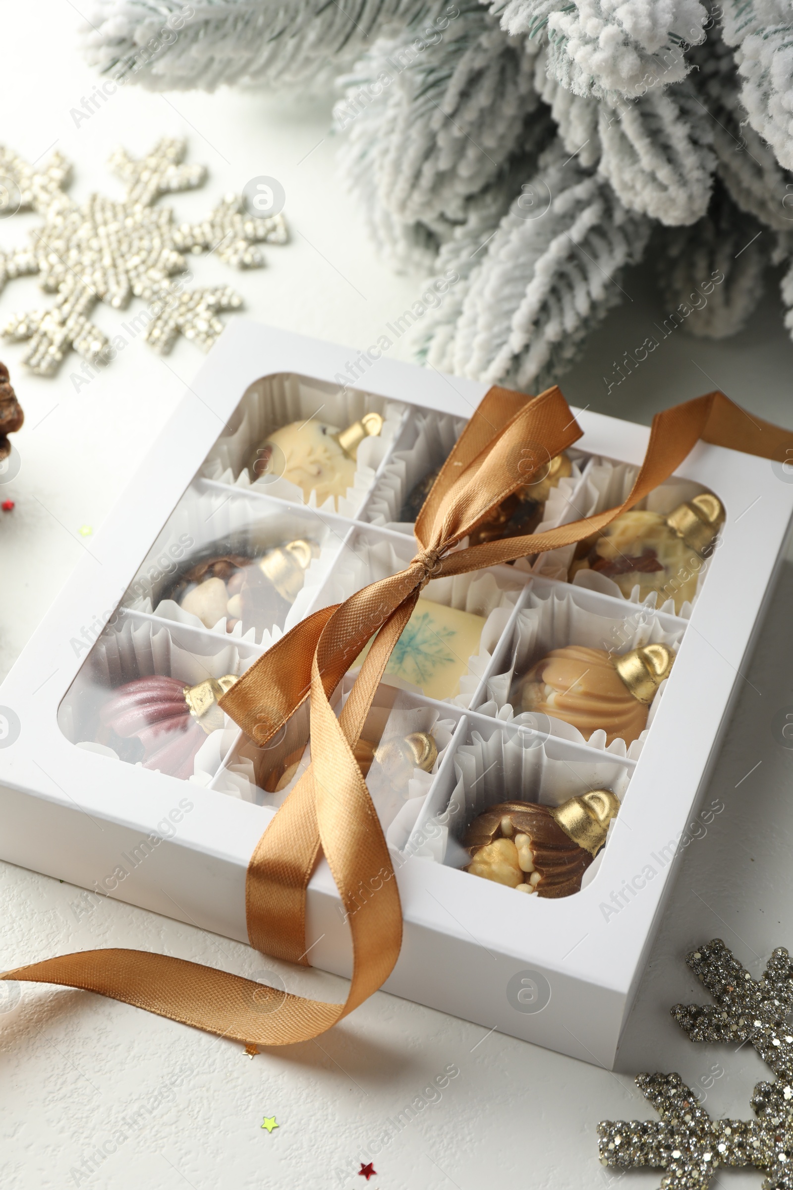 Photo of Box with tasty chocolate candies in shape of baubles and Christmas decor on white background, closeup