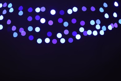 Photo of Blurred view of colorful lights on black background, bokeh effect