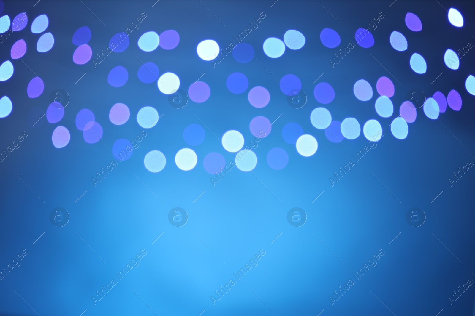 Photo of Blurred view of colorful lights on light blue background, bokeh effect