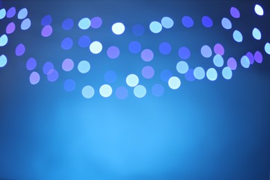 Photo of Blurred view of colorful lights on light blue background, bokeh effect