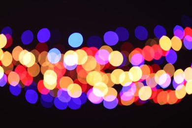 Photo of Blurred view of colorful lights on black background, bokeh effect