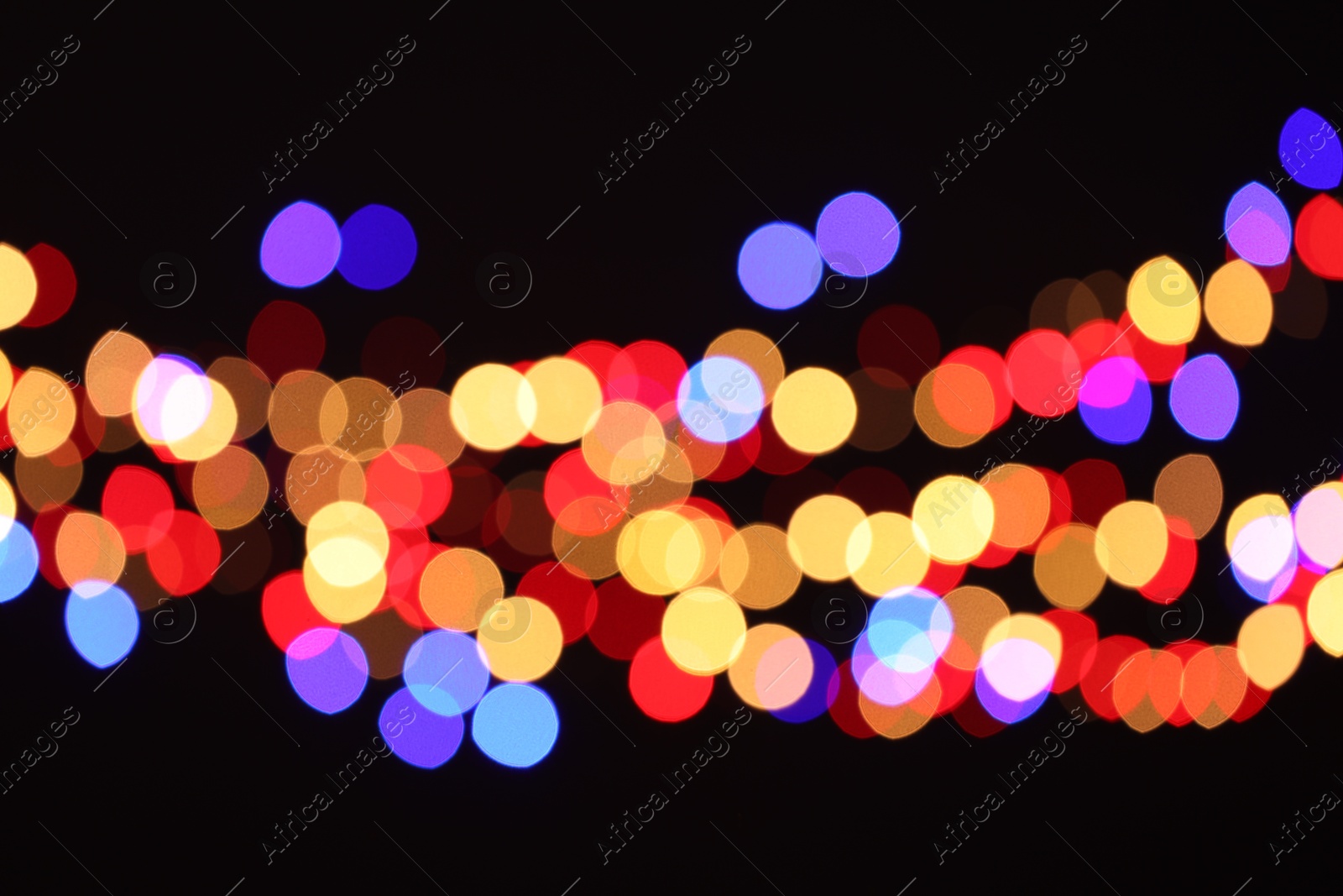 Photo of Blurred view of colorful lights on black background, bokeh effect