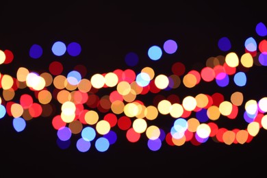 Photo of Blurred view of colorful lights on black background, bokeh effect