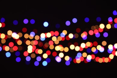 Photo of Blurred view of colorful lights on black background, bokeh effect