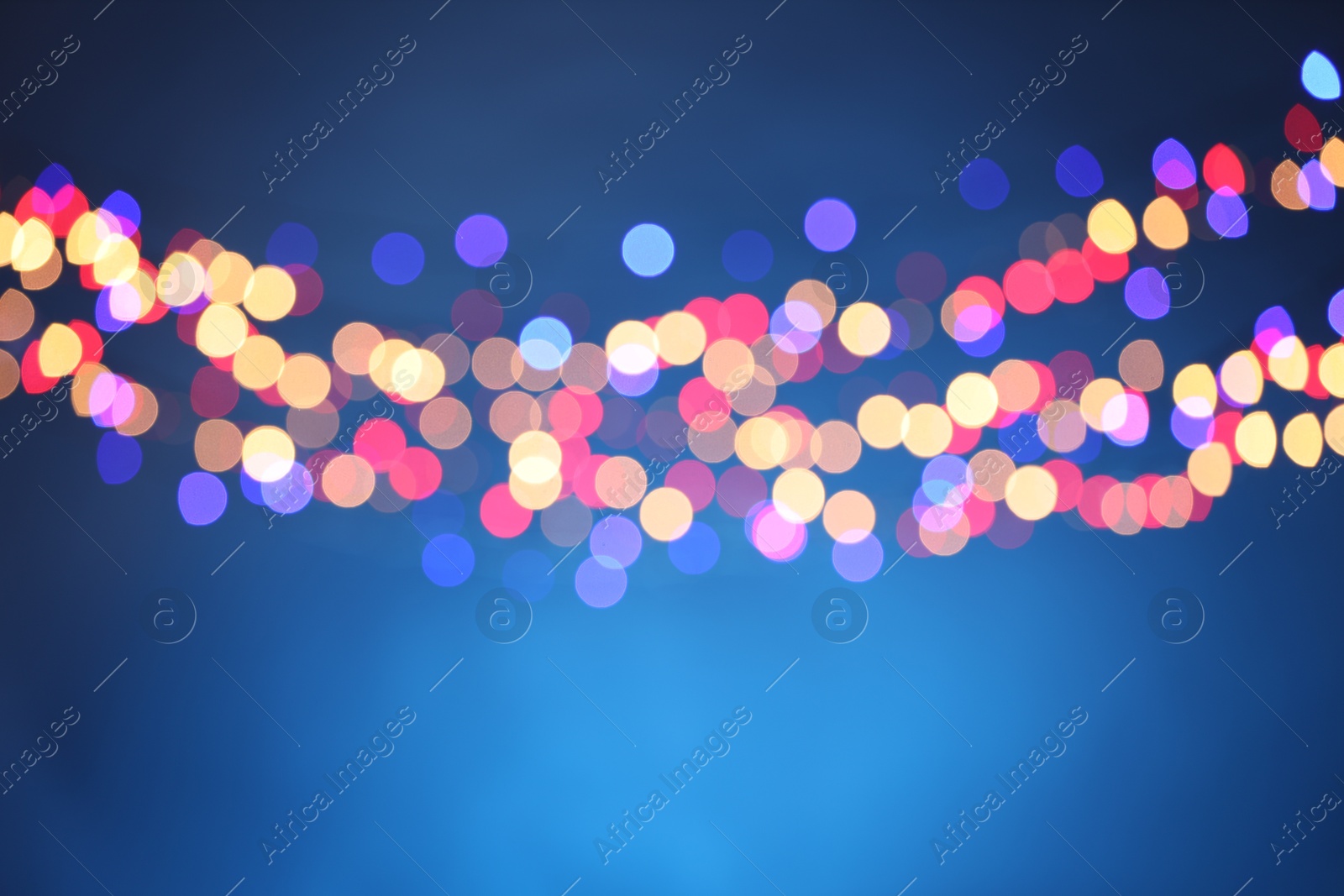 Photo of Blurred view of colorful lights on light blue background, bokeh effect