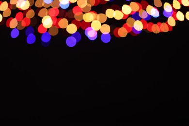 Photo of Blurred view of colorful lights on black background, space for text. Bokeh effect