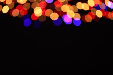 Photo of Blurred view of colorful lights on black background, space for text. Bokeh effect