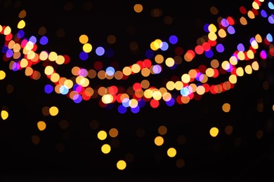 Photo of Blurred view of colorful lights on black background, bokeh effect