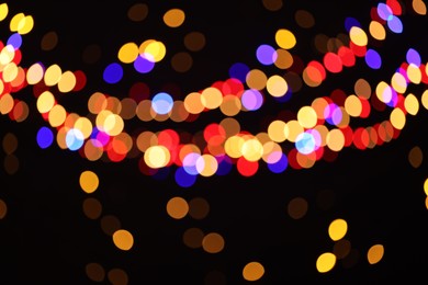 Photo of Blurred view of colorful lights on black background, bokeh effect