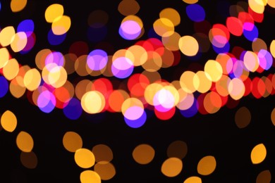 Photo of Blurred view of colorful lights on black background, bokeh effect