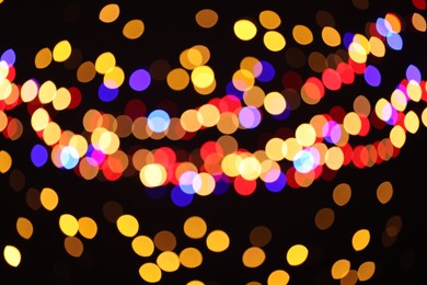 Photo of Blurred view of colorful lights on black background, bokeh effect