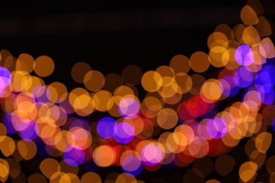 Photo of Blurred view of colorful lights on black background, bokeh effect