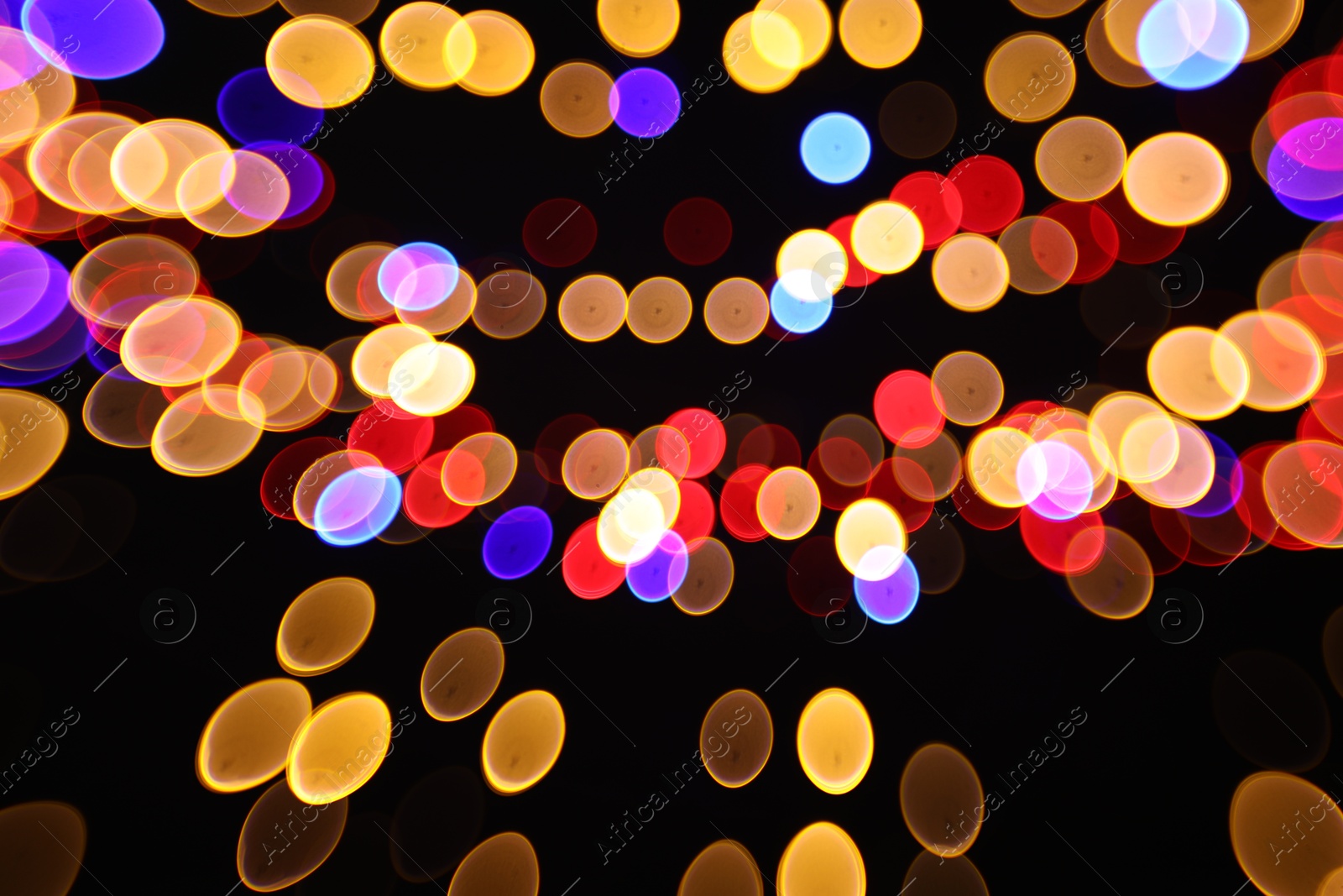 Photo of Blurred view of colorful lights on black background, bokeh effect