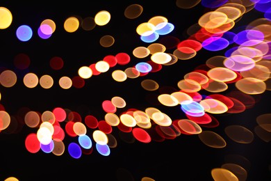 Photo of Blurred view of colorful lights on black background, bokeh effect