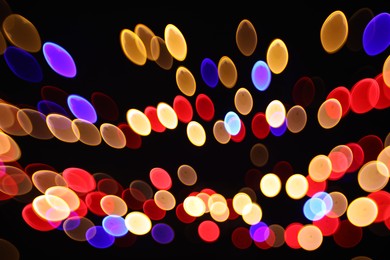 Photo of Blurred view of colorful lights on black background, bokeh effect