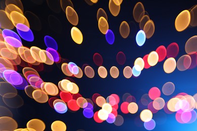 Photo of Blurred view of colorful lights on dark blue background, bokeh effect