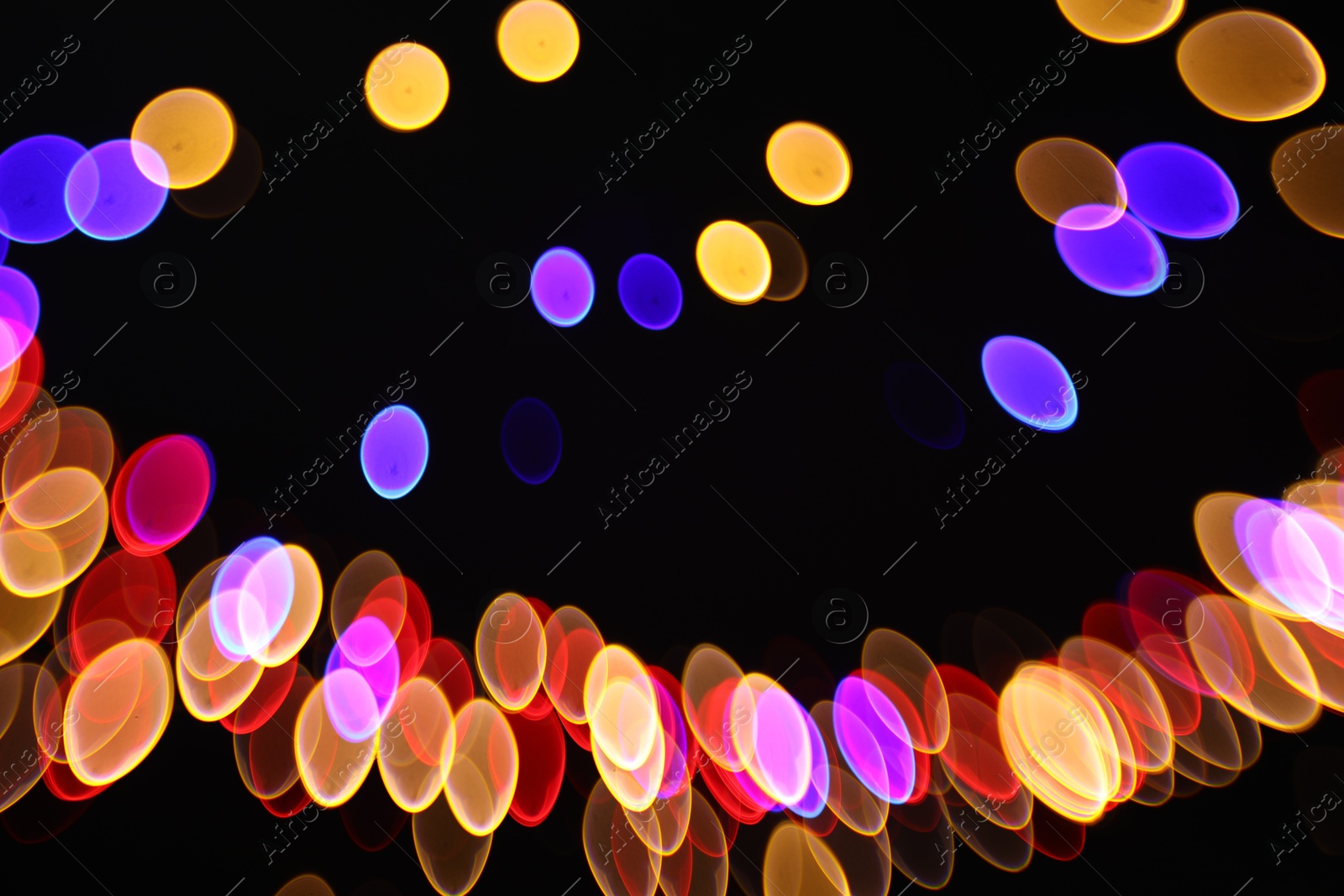 Photo of Blurred view of colorful lights on black background, bokeh effect