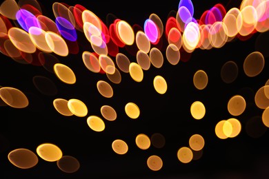 Photo of Blurred view of colorful lights on black background, bokeh effect