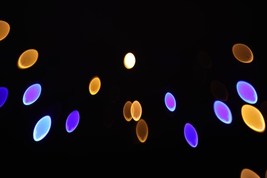 Photo of Blurred view of colorful lights on black background, bokeh effect