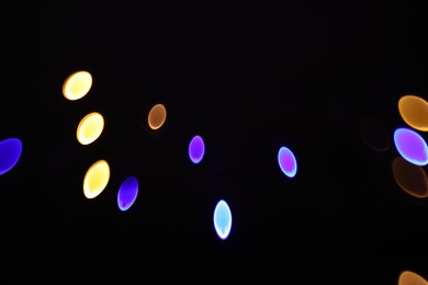 Photo of Blurred view of colorful lights on black background, bokeh effect