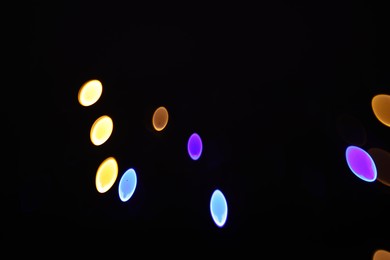 Photo of Blurred view of colorful lights on black background, bokeh effect