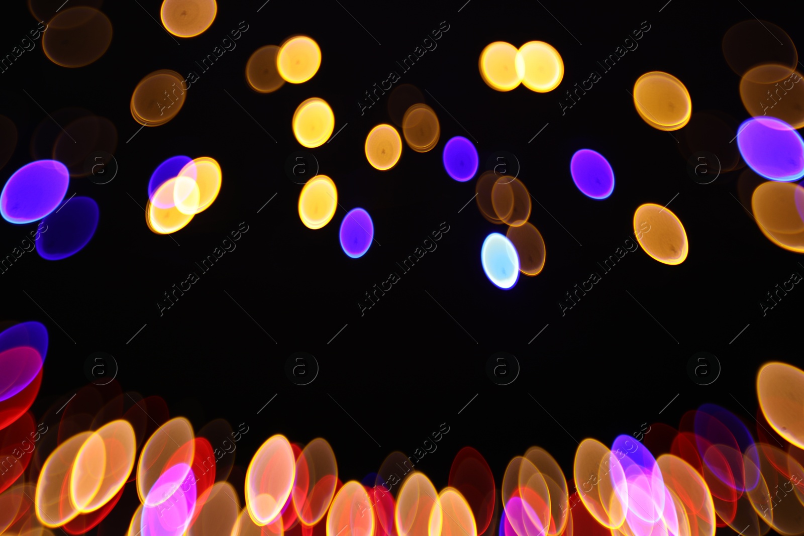 Photo of Blurred view of colorful lights on black background, bokeh effect