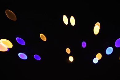 Photo of Blurred view of colorful lights on black background, bokeh effect