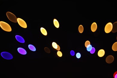 Photo of Blurred view of colorful lights on black background, bokeh effect