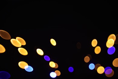 Photo of Blurred view of colorful lights on black background, bokeh effect