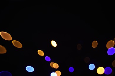 Photo of Blurred view of colorful lights on black background, bokeh effect