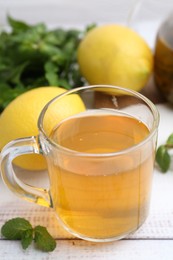 Photo of Aromatic mint tea with lemons and fresh leaves on white wooden table, closeup