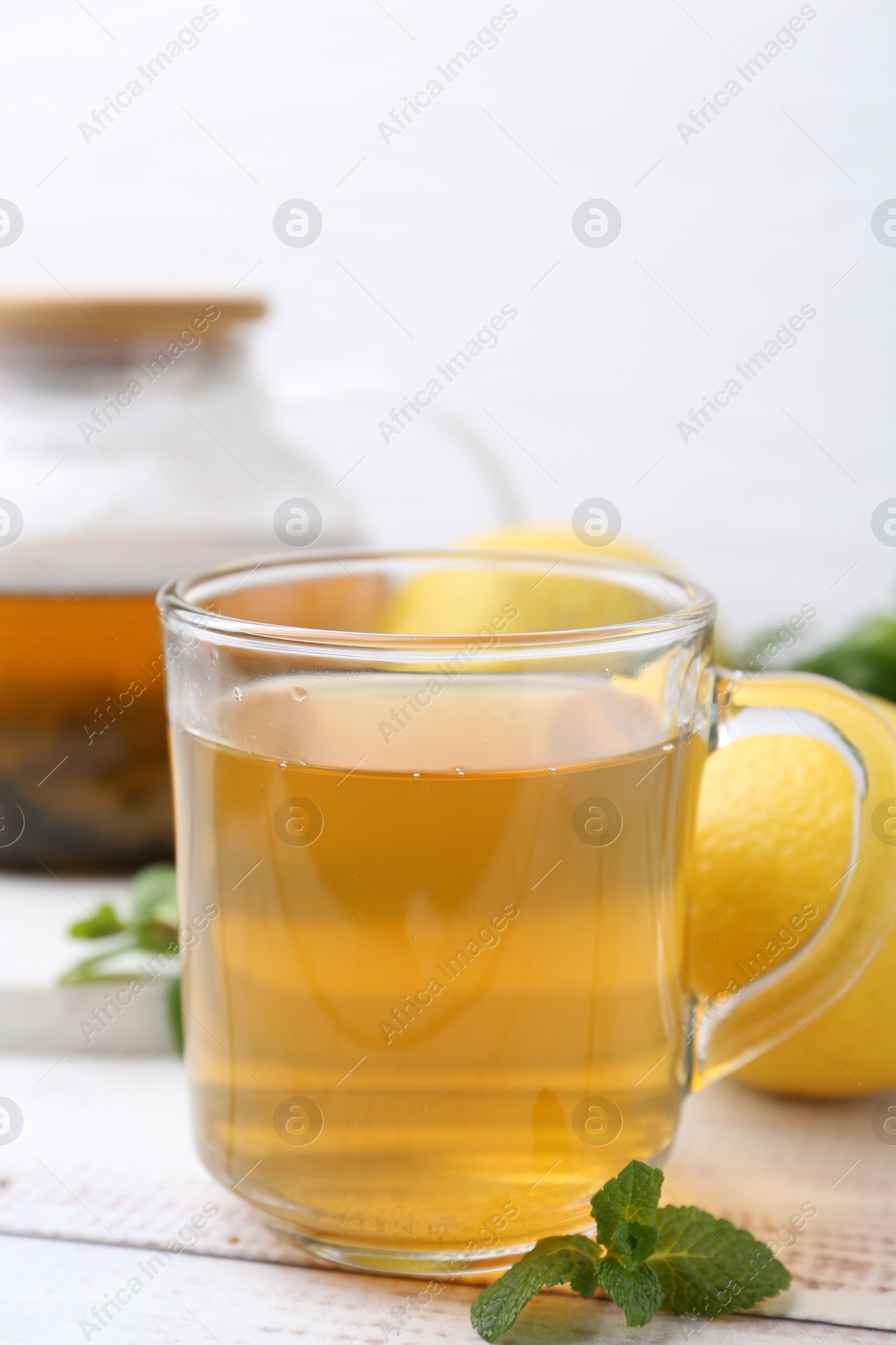 Photo of Aromatic mint tea with lemons and fresh leaves on white wooden table, closeup