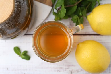 Photo of Aromatic mint tea with lemons and fresh leaves on white wooden table, flat lay