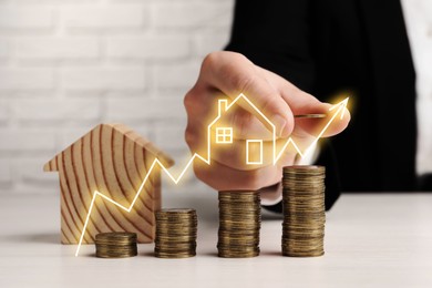 Image of Real estate market. Man stacking coins at table, closeup. Graphic with illustration of house visualizing interest rate rise