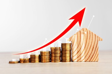 Image of Real estate market. Stacked coins and house model on table. Graphic and arrow visualizing interest rate rise