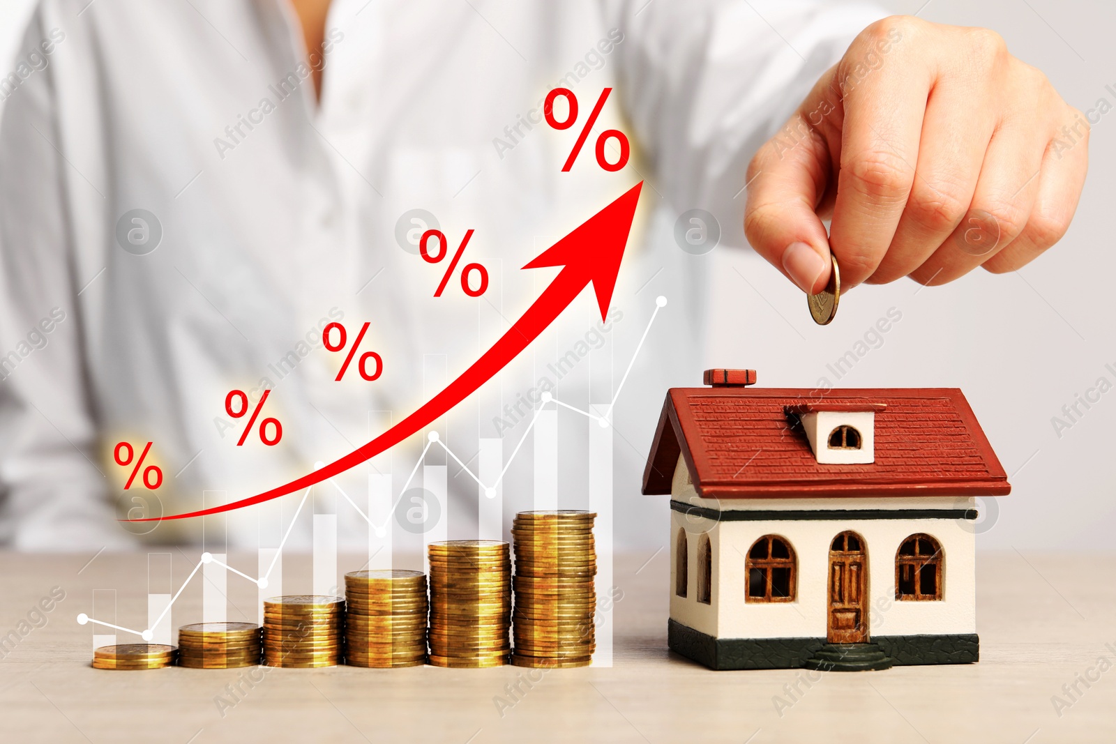 Image of Real estate market. Woman putting coin into house shaped money box at table, closeup. Graphic and arrow visualizing interest rate rise