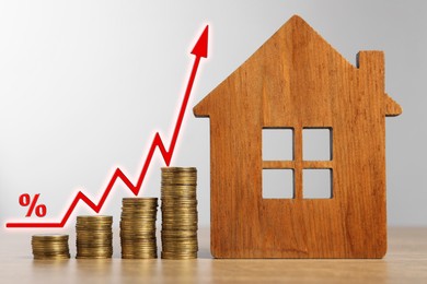 Image of Real estate market. Stacked coins and house model on table. Arrow and percent sing visualizing interest rate rise