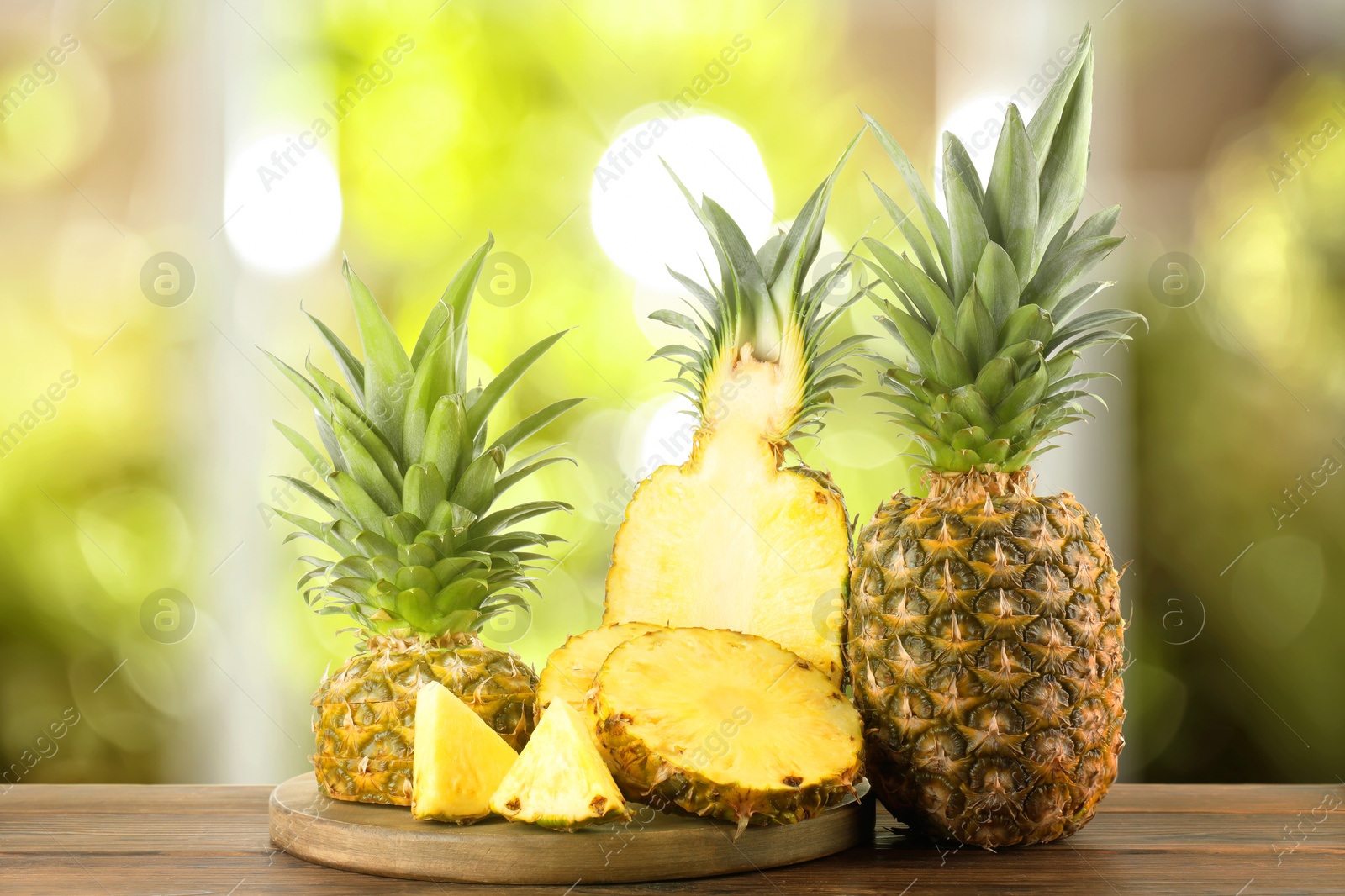 Image of Fresh ripe pineapples on wooden table indoors