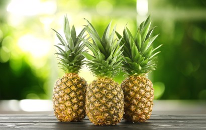 Image of Fresh ripe pineapples on wooden table indoors