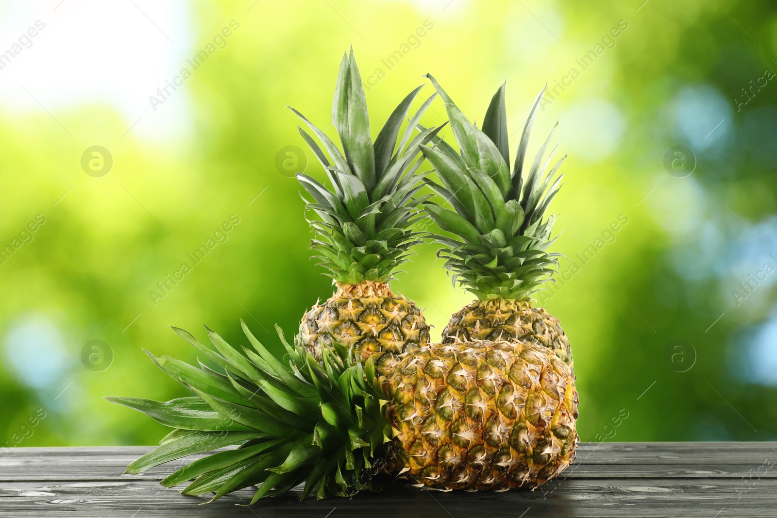 Image of Fresh ripe pineapples on wooden table outdoors