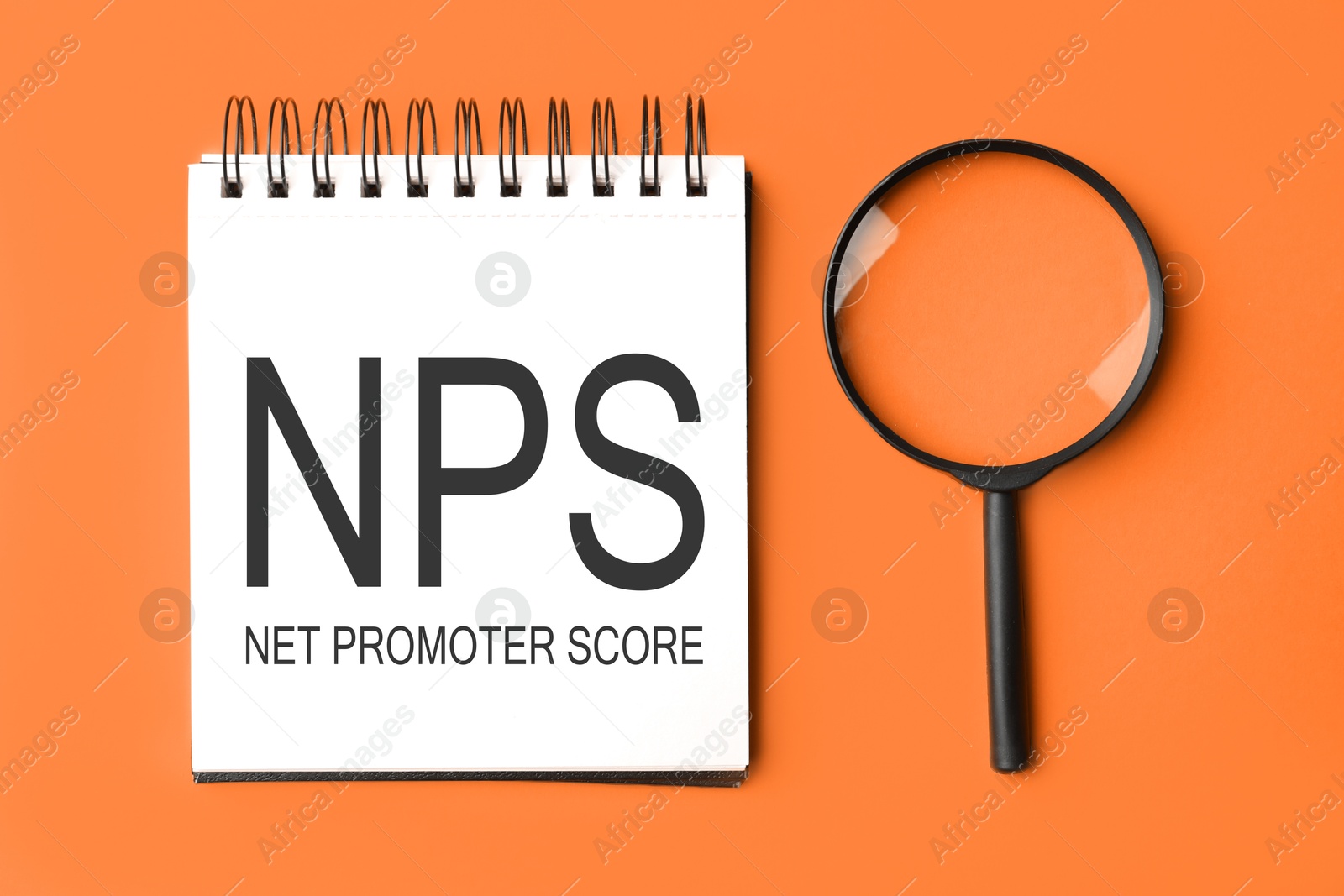 Image of NPS (net promoter score) in notebook and magnifying glass on orange background, top view. Customer satisfaction assessment