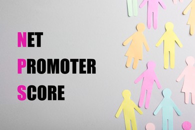 Image of Net Promoter Score (NPS) words and many colorful paper human figures on grey background, top view. Customer satisfaction assessment