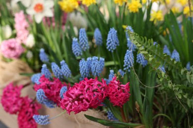 Photo of Many different flowers in wooden crate, closeup. Spring season