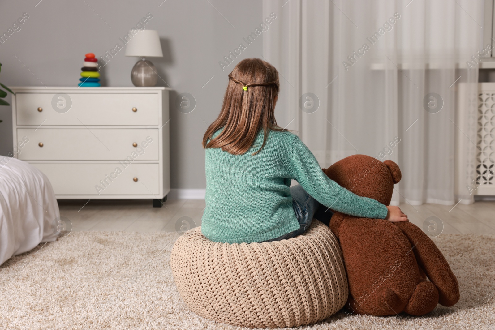 Photo of Autism concept. Lonely little girl with teddy bear at home, back view