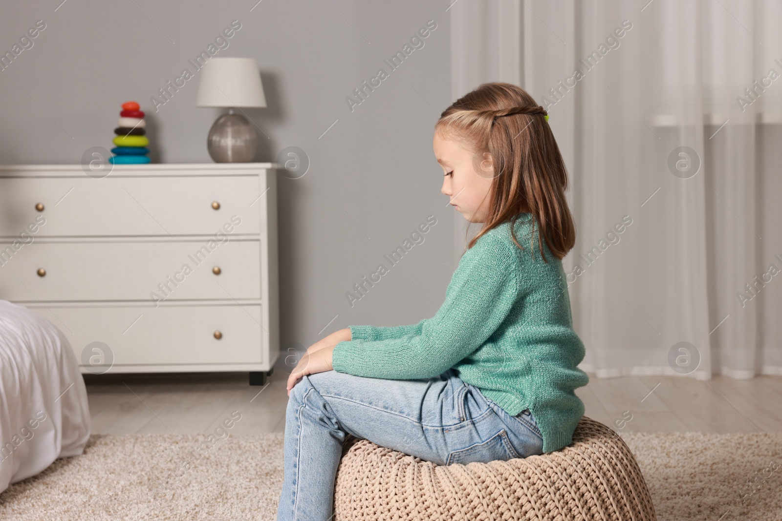 Photo of Autism concept. Lonely little girl on pouf at home