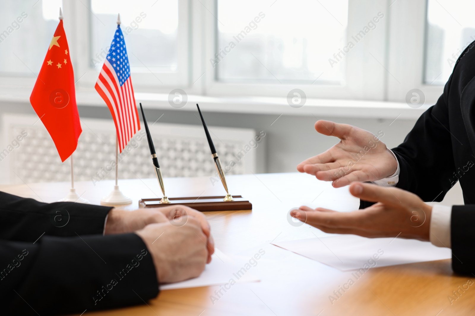 Photo of Diplomats negotiating during meeting at table indoors, closeup